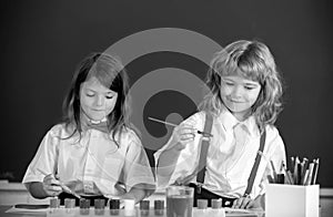 School children drawing a colorful pictures with pencil crayons in classroom. Portrait of cute pupils enjoying art and