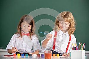 School children drawing a colorful pictures with pencil crayons in classroom. Portrait of cute pupils enjoying art and