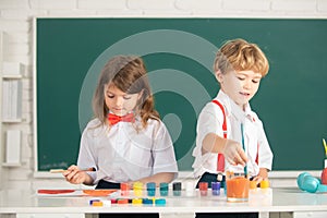School children drawing a colorful pictures with pencil crayons in classroom. Portrait of cute pupils enjoying art and