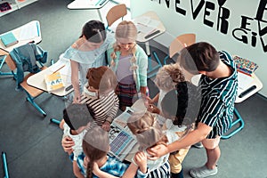 School children forming a circle around their teacher.