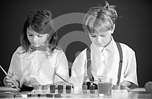 School children girl and boy painting with paints color and brush in classroom.