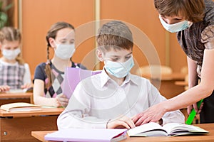 School children with protective masks against coronavirus at lesson in classroom