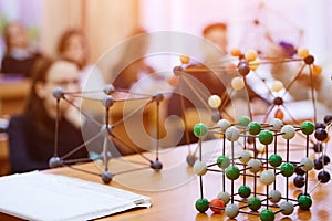 School children in a science class with a molecular model. Background image with soft focus. Education concept