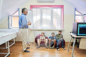 School children smiling to their senior teacher who telling about space