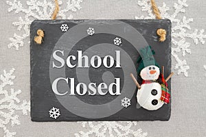 School Closed message on a chalkboard sign with a snowman