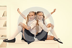 School club. Little schoolgirls classmates friendly kids. Schoolgirls friends sit on desk. Best friends relaxing photo