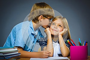 School Communication concept. boy whispering in ear of girl