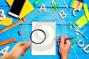 school concept, accessories. the schoolboy points to a notepad. hand with magnifying glass. new ideas, homework solution. back to