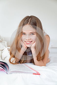 School concept. little girl with book lying on bed