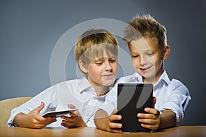 School concept. Smiling happy boys sitting at the desk and keep ebooks