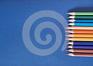 School desk blue background with different colored crayons. Copy space.