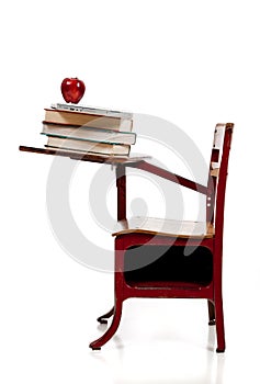 A school desk with books, computer and apple