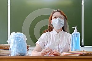 The school doctor sits in the classroom and distributes medical masks. School nurse handles hands with a sanitizer, copy space