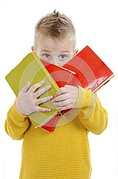 School, educatiLittle shy or scared student boy hiding behind books. Adorable little boy on first day at school.