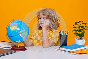 School and education concept. Portrait of cute child school boy looking at globe during geography lesson isolated on