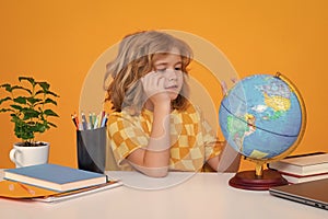 School and education concept. Portrait of cute child school boy looking at globe during geography lesson isolated on