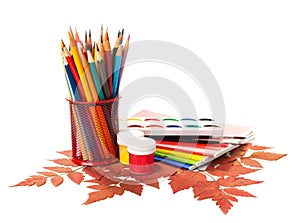 School equipment with pencils, paints , brushes and autumn leaves.