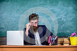 School exam concept. Examiner full of doubts sit at table chalkboard background. Tricky examinator hesitates about mark