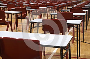 School exam room or hall set up with multiple tables, desks and chairs