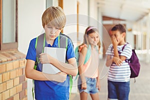 School friends bullying a sad boy in corridor