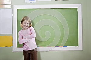 School girl in classroom standing by blackboard