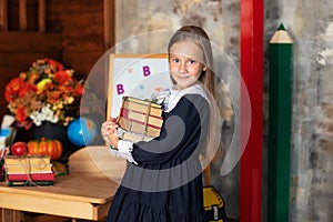 School Girl in dress holds a stack of books.