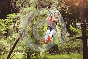 School girl enjoying activity in a climbing adventure park on a summer day