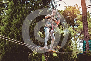 School girl enjoying activity in a climbing adventure park on a summer day