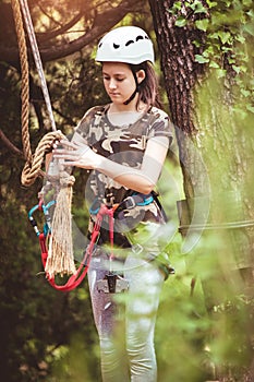 School girl enjoying activity in a climbing adventure park on a summer day