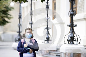 School girl with face mask in front of her school