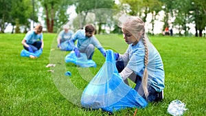 School girl with group of eco volunteers picking up litter park, saving nature