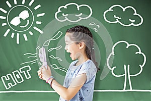 school girl holding fan and standing against chalkboard