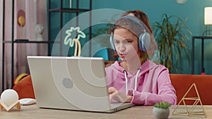 School girl looking at laptop camera, making video webcam conference call with friends or teacher