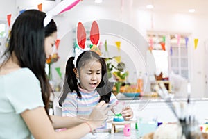 School girl with mother painting Plaster doll