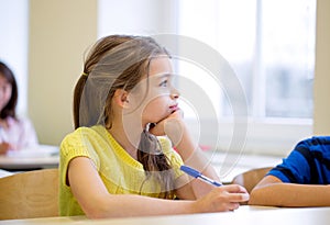 School girl with pen being bored in classroom