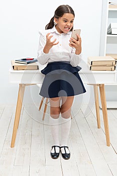 school girl with phone in classroom, anger. school girl with phone at the desk. school girl