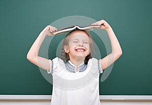 School girl read book, posing at school board, empty space, education concept