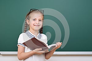 School girl read book, posing at school board, empty space, education concept