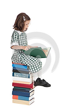 School girl sitting on book pile reading