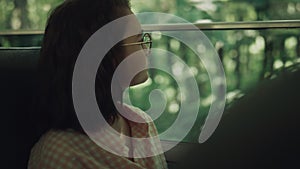 School girl sitting bus alone close up. Teen brunette looking window on greenery