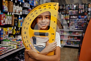 School girl student holding huge protractor ruler stationery in hands