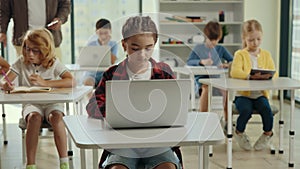 School girl is studying using laptop sitting in the class room during computer science lesson. Elementary school