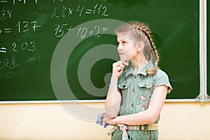School girl thinking at blackboard