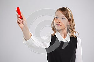 A school girl writes on a blackboard with red chalk