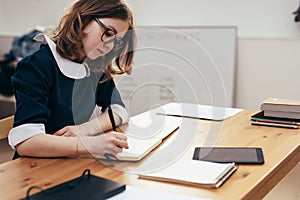 School Girl writes in a notebook sitting at table Classwork, homework