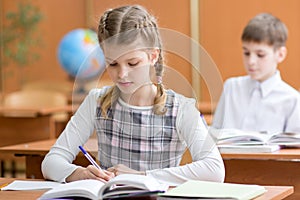 School girl writing in notebook in classroom