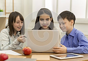 School girls and boy playing on laptop in school