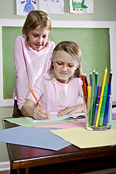 School girls writing in notebook in classroom