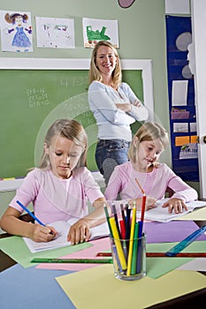School girls writing in notebooks with teacher photo