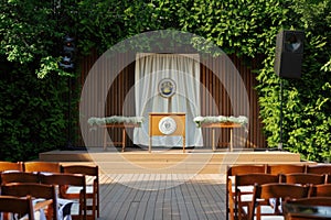 School graduation scene with wooden podium and chairs adorned with caps and diplomas